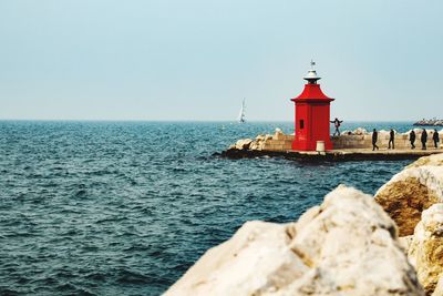 Lighthouse by sea against clear sky