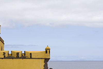 Buildings by sea against sky