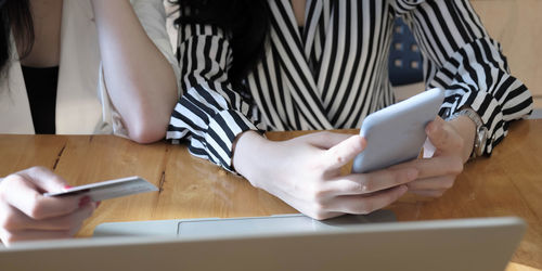 Midsection of man using mobile phone on table