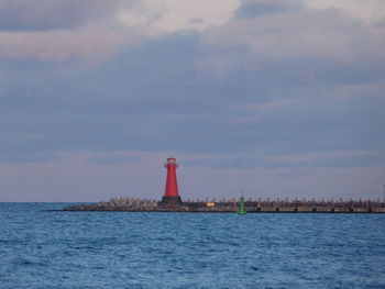 Lighthouse by sea against sky