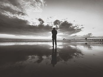 Silhouette man standing on beach against sky