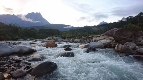 Rocks by river against sky