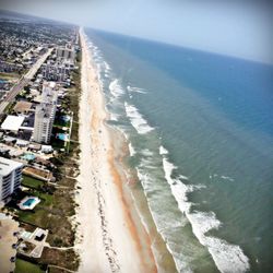 Aerial view of city by sea against sky