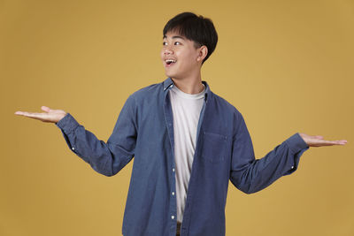 Portrait of young man standing against orange background