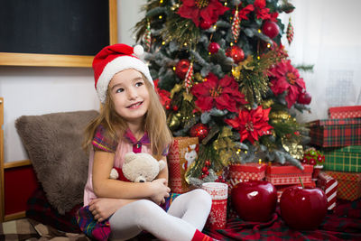 Portrait of girl sitting on christmas tree