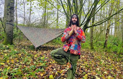 Portrait of young woman standing against trees