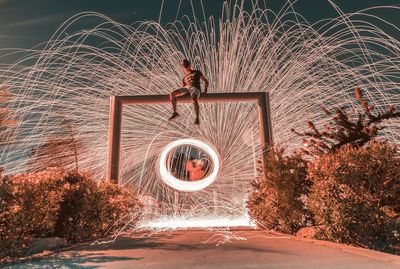 Low angle view of boy against light painting against sky at night