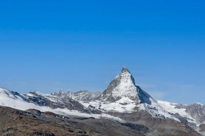 Scenic view of snowcapped mountains against clear blue sky