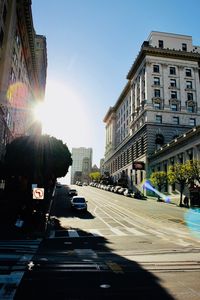 Cars on city street against bright sun