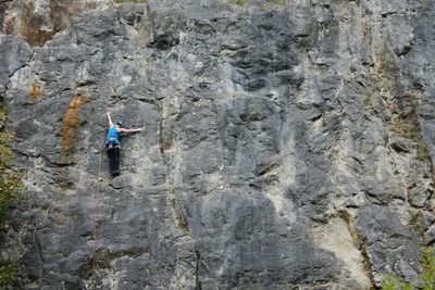 Rear view of person climbing on rocky mountain