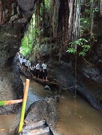 Group of people on rock by river in forest