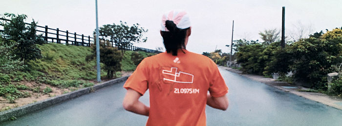 Rear view of man standing on road against trees