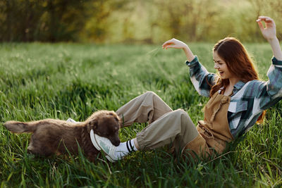 Side view of woman with dog on grassy field