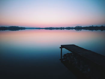 Scenic view of calm lake and dock at sunset