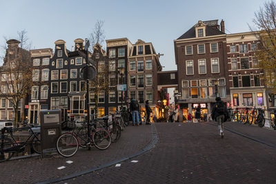 Bicycles on road by buildings in city against sky