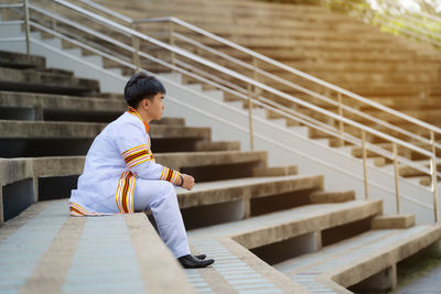 Side view of young man sitting on staircase