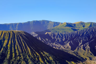 Panoramic view of volcanic mountains against clear blue sky