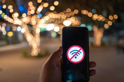 Low section of person holding mobile phone in city