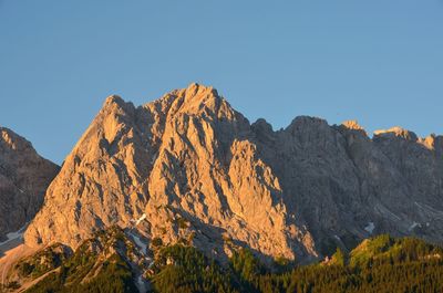 Low angle view of rocky mountains against clear blue sky