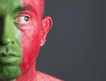 Close-up of man with portuguese flag body paint against black background