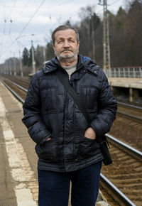 Portrait of man in warm clothing standing on railroad station platform