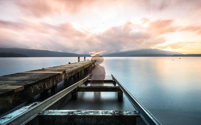 Pier on sea against cloudy sky