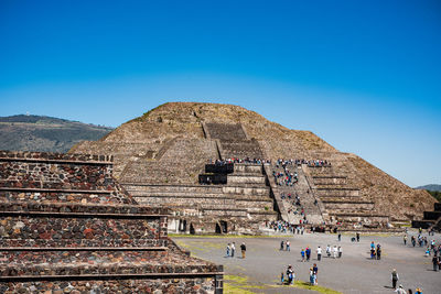 Group of people in front of historical building against blue sky