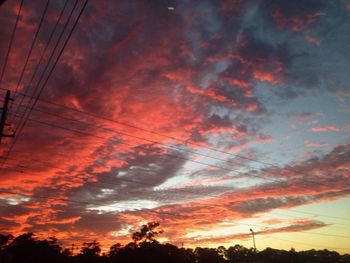 Low angle view of power lines against cloudy sky