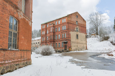 Buildings by snow covered houses against sky