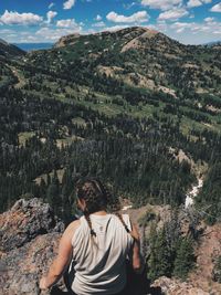 Rear view of man standing on rock against sky