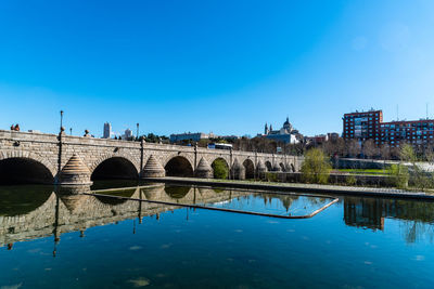 Arch bridge over river against blue sky