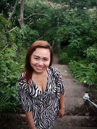 Portrait of smiling woman standing against plants