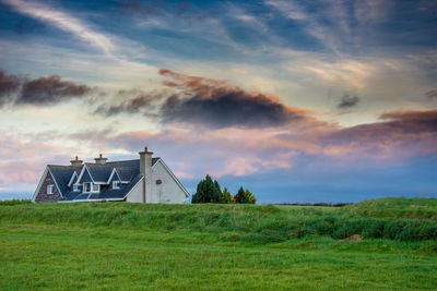 House on field against sky during sunset