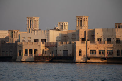 Buildings by sea against clear sky