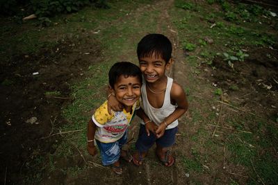 High angle portrait of smiling siblings standing on field