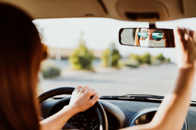 Woman adjusting rear-view mirror in car