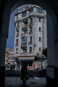 Rear view of man walking on street by buildings