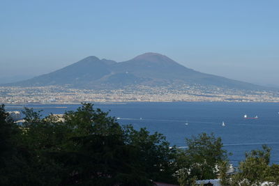 Scenic view of sea and mountains against clear blue sky