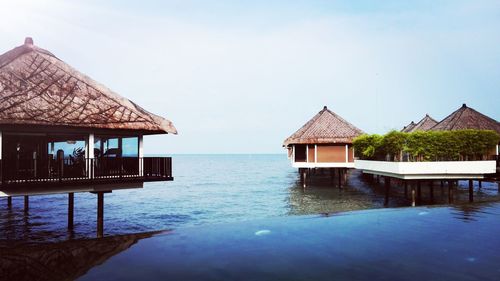 Stilt houses in sea against clear sky