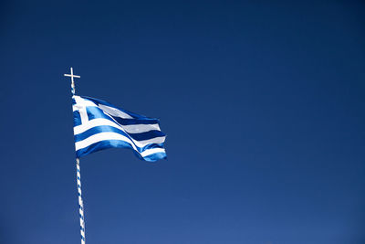 Low angle view of flag against clear blue sky