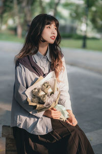 Young woman using mobile phone while standing on road