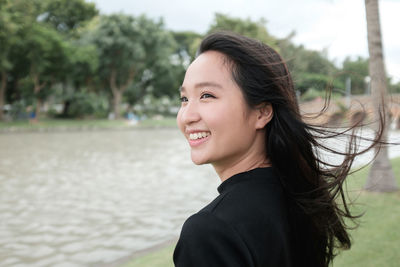 Close-up of smiling woman by lake