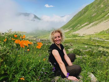 Portrait of smiling woman sitting on mountain