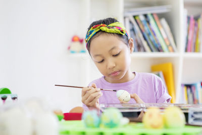 Girl painting easter egg at home