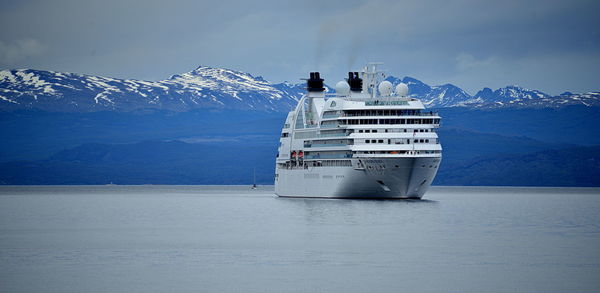 Scenic view of sea by snowcapped mountains against sky