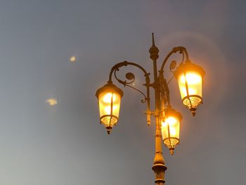 Low angle view of illuminated street light against sky