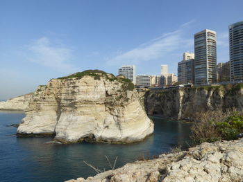 Sea by buildings against sky