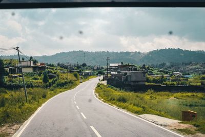 Road leading towards city against sky