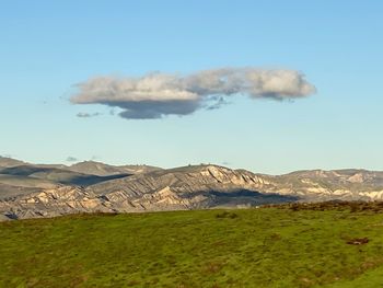 Scenic view of field and mountains against sky