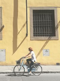 Woman riding bicycle by building